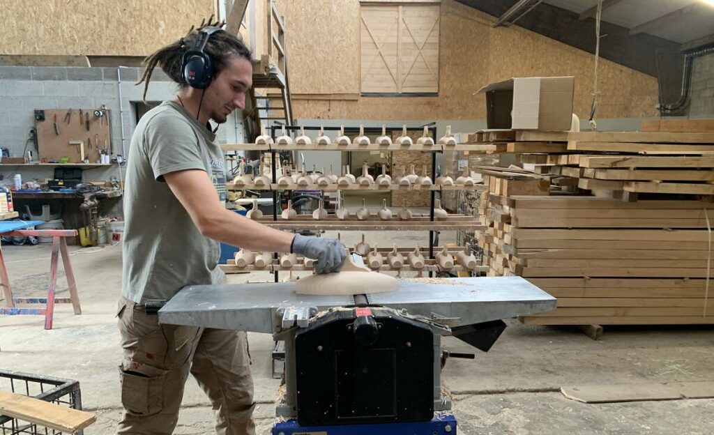 Artisan qui fabrique un bateau en bois dans l'atelier de la Maison Tirot